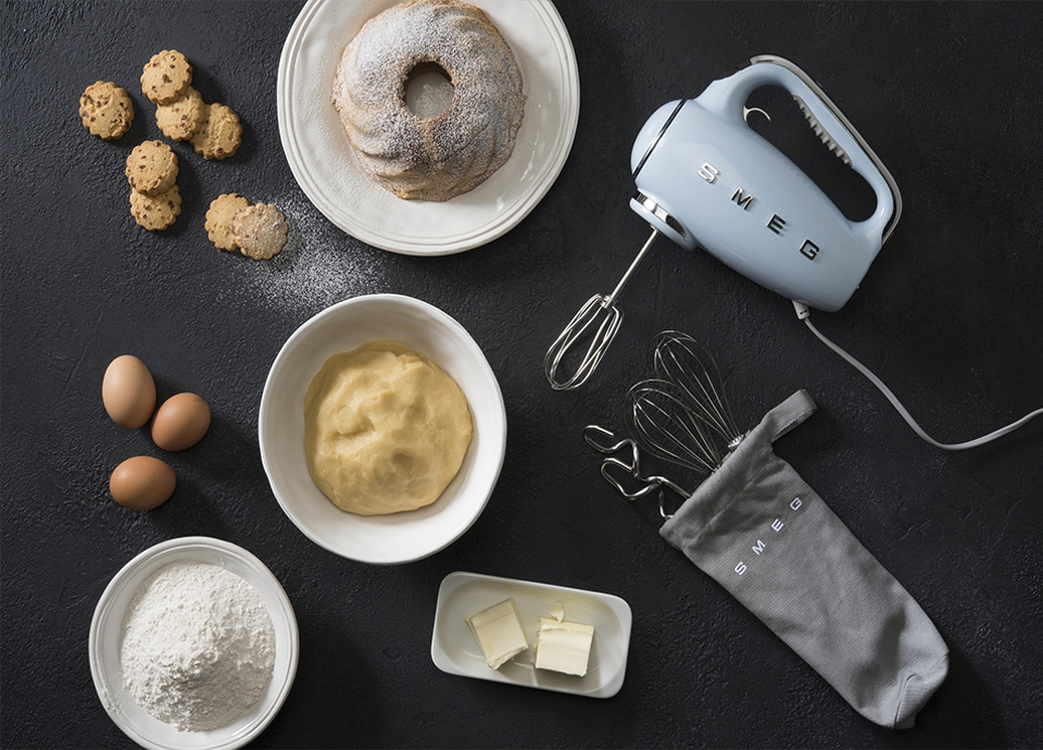 Electric hand mixer in pastel blue on a black benchtop