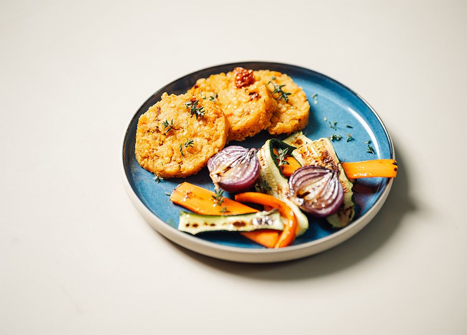 Burgers di lenticchie serviti con verdure grigliate su un piatto rustico