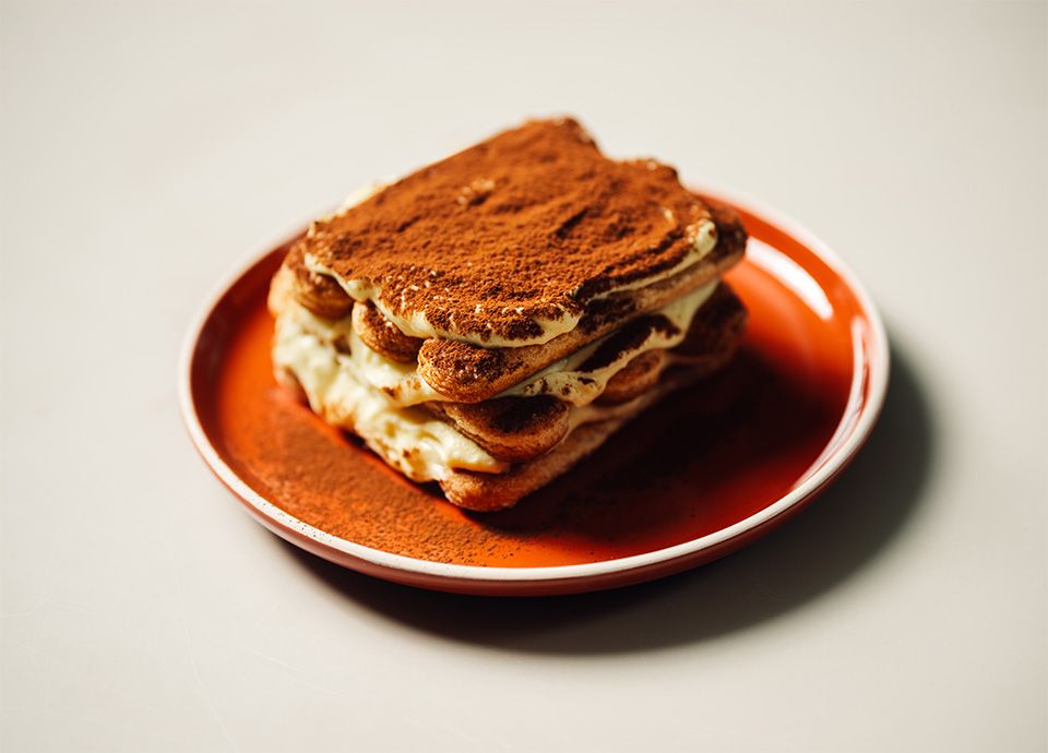 Tiramisù classico servito in piatti color terracotta caldi