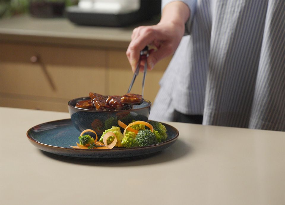 Persona che mette il tofu cotto alla teriyaki su un piatto di ceramica
